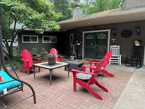 Eine Terrasse mit roten Adirondack-Stühlen, einem Tisch und einem Blumentopf.
