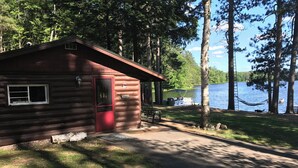 Eine Hütte mit roter Tür, einem Fenster und einem Schild, das anzeigt, dass es sich um einen Campingplatz handelt.