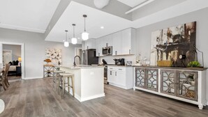 A modern kitchen with white cabinets, a central island, and pendant lighting. - Luxurious Downtown-2 bed 2 bath Corner 2M (Nashville)