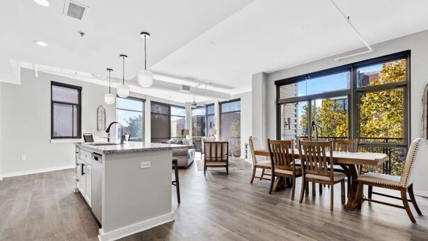 A spacious kitchen with a central island, large windows, and a dining area with wooden chairs. - Luxurious Downtown-2 bed 2 bath Corner 2M (Nashville)