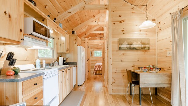 L’intérieur d’une cabane en bois comprend une cuisine, un coin repas et un lit.
