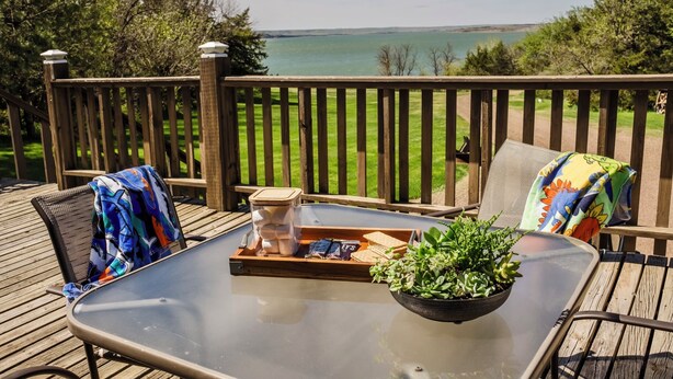 Eine Terrasse mit einem Glastisch, Stühlen, einer Serviertablett mit Snacks und einem Blumentopf.