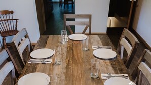 Ein Holzespeisetisch ist für sechs Personen gedeckt, mit weißen Tellern, Besteck und Gläsern.