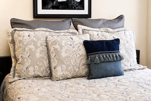 A bed with a floral patterned bedspread, two grey pillows, and a dark blue pillow with tassels. - Casa di Vino - Backyard BBQ near Messina Hof (Bryan)