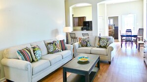 Uma sala de estar com dois sofás, uma mesa de centro e um espaço de jantar com cadeiras e mesa.