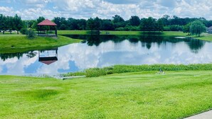 Um parque tranquilo com um coreto, um lago e um gramado bem cuidado.