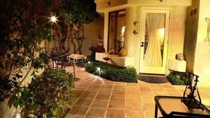 Un patio con zona de comedor, una puerta con cortina y adornos.