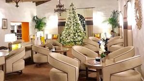 Amplia sala de estar con techos altos y vigas a la vista, con asientos cómodos y un gran árbol de Navidad decorado.