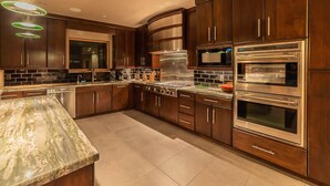 A modern kitchen with dark wood cabinets, stainless steel appliances, and a marble countertop.