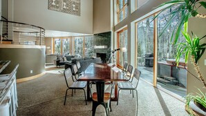 A spacious living area with a large dining table, comfortable seating, and a fireplace.