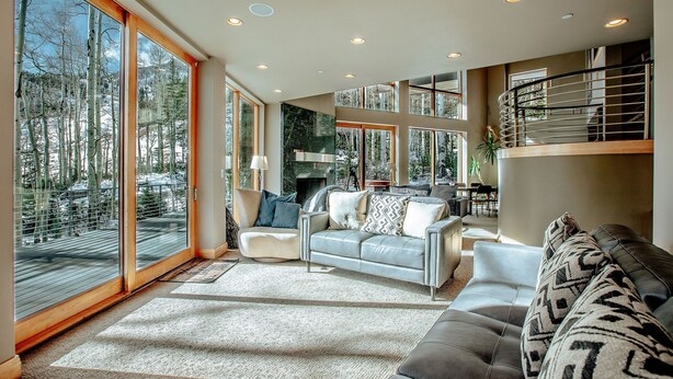 A spacious living room with a large window, a sofa, and a staircase.
