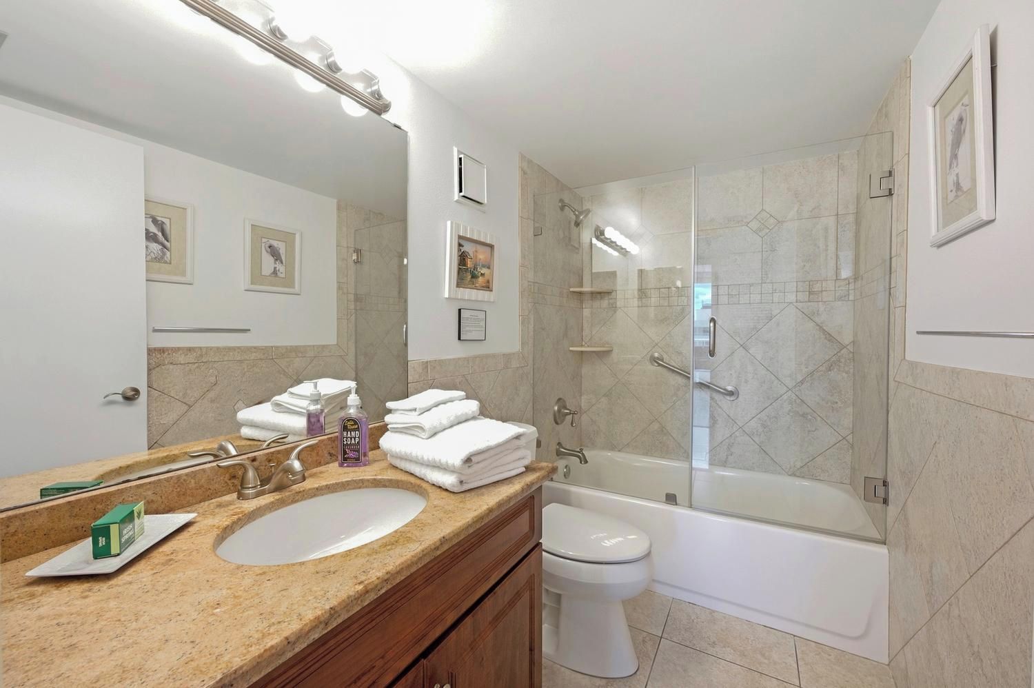 A bathroom with a sink, mirror, toilet, and bathtub.
