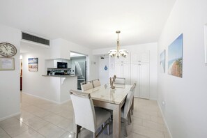 A modern kitchen with a built-in microwave, stainless steel refrigerator, and a dining area with a glass table and chairs. - SEA MAR CONDO: 19th Floor Penthouse South Seas Tower 4 With Awesome Views (Marco Island)