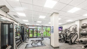 Une salle de sport équipée de divers appareils d’exercice, d’un banc et d’un tapis de course.