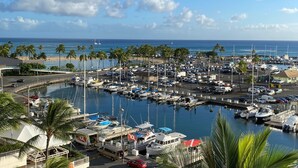 A marina with boats docked, a beach in the background, and palm trees. - Ocean View Condo - Ilikai Marina Waikiki Honolulu (Honolulu)