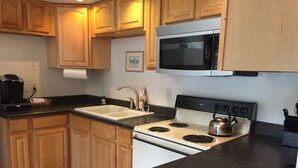 A kitchen with wooden cabinets, a stainless steel stove, a microwave, and a sink.