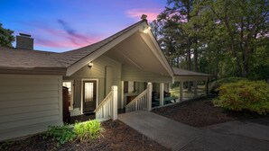 A house with a covered porch, a front door, and a staircase leading to the entrance.