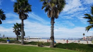 Ein Strand mit Palmen, einem Volleyballnetz und spielenden Menschen.