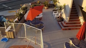 Ein Poolbereich mit Sprungbrett, Liegestühlen und einer Treppe, die zu einem oberen Deck führt.