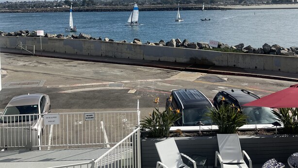 Ein Yachthafen mit Segelbooten, ein Poolbereich mit Liegestühlen und Blick auf die Küste.
