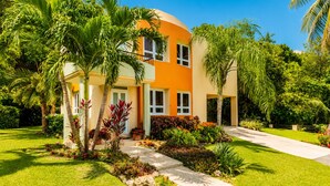 A modern two-story house with a curved roof, surrounded by lush greenery and palm trees. - Surfing Privacy and Relaxation!  Wi-Fi, full A/C! (Rincon)
