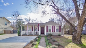 A single-story house with a front porch, a flag, and a well-maintained front yard. - Howdy Headquarters~ A Backyard Gathering Like no Other! (College Station)