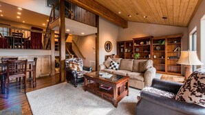 A spacious living room with a high ceiling, wooden staircase, and a cozy fireplace. - Wonderful Park City Townhome | Hot Tub | Mountain Views | Private Garage (Park City)