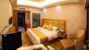 A hotel room with a large bed, a desk with a computer, a chair, and a small table with a plant. - Xiamen Plaza Hotel (Xiamen)