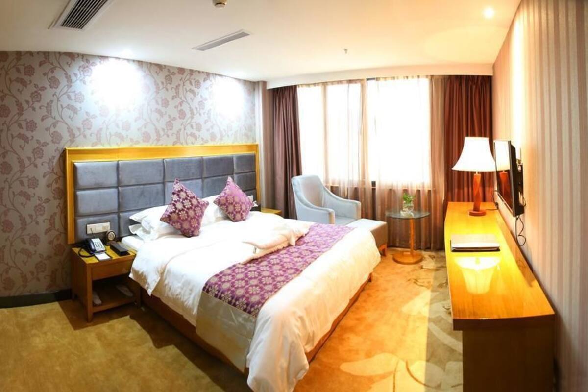 Une chambre d’hôtel avec un grand lit, une table de chevet avec une lampe, une chaise et un bureau avec une lampe.