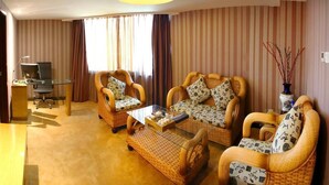A hotel room with striped wallpaper, a sofa set, a small table with a tray, a desk with a computer, and a vase with branches. - Xiamen Plaza Hotel (Xiamen)