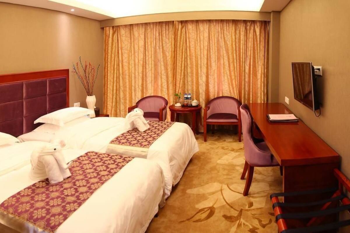 Une chambre d’hôtel avec deux lits, un bureau, une chaise et un téléviseur.