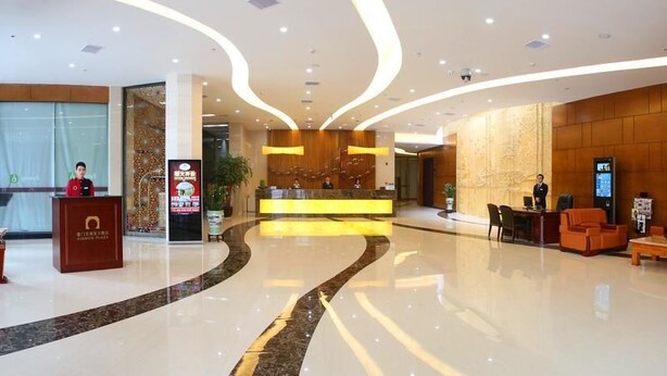 A modern hotel lobby with a reception desk, seating area, and a large digital screen. - Xiamen Plaza Hotel (Xiamen)