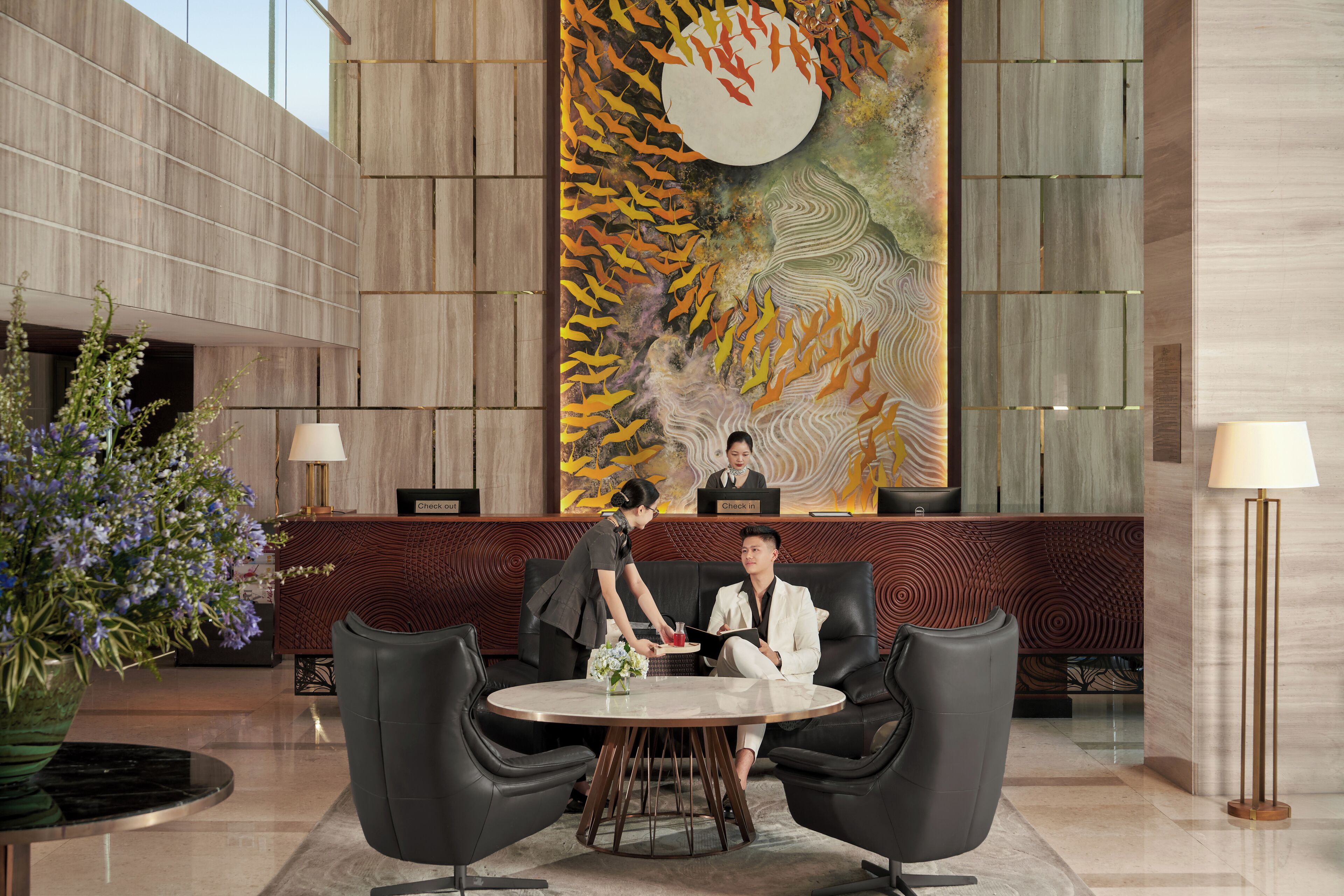 A lobby with a reception desk, two seating areas, and a large abstract mural on the wall.