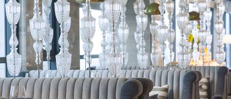 Une rangée de fauteuils et de canapés moelleux dans un intérieur moderne, agrémentée de lustres en cristal suspendus.