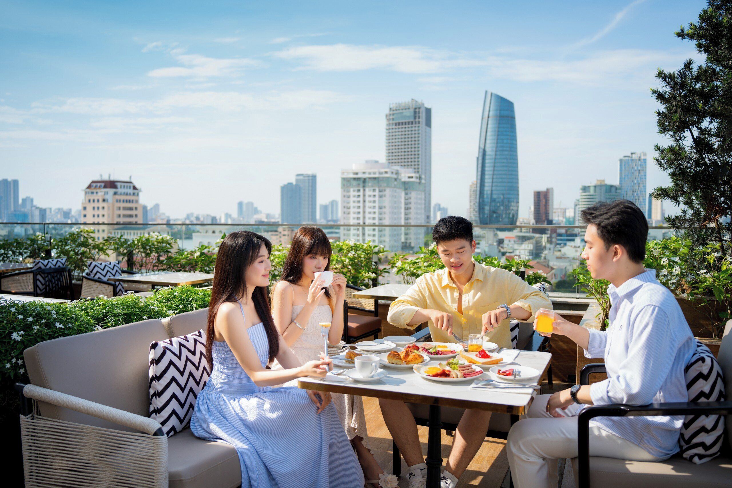 A rooftop dining area with a city skyline view, outdoor seating, and a table set for four people.