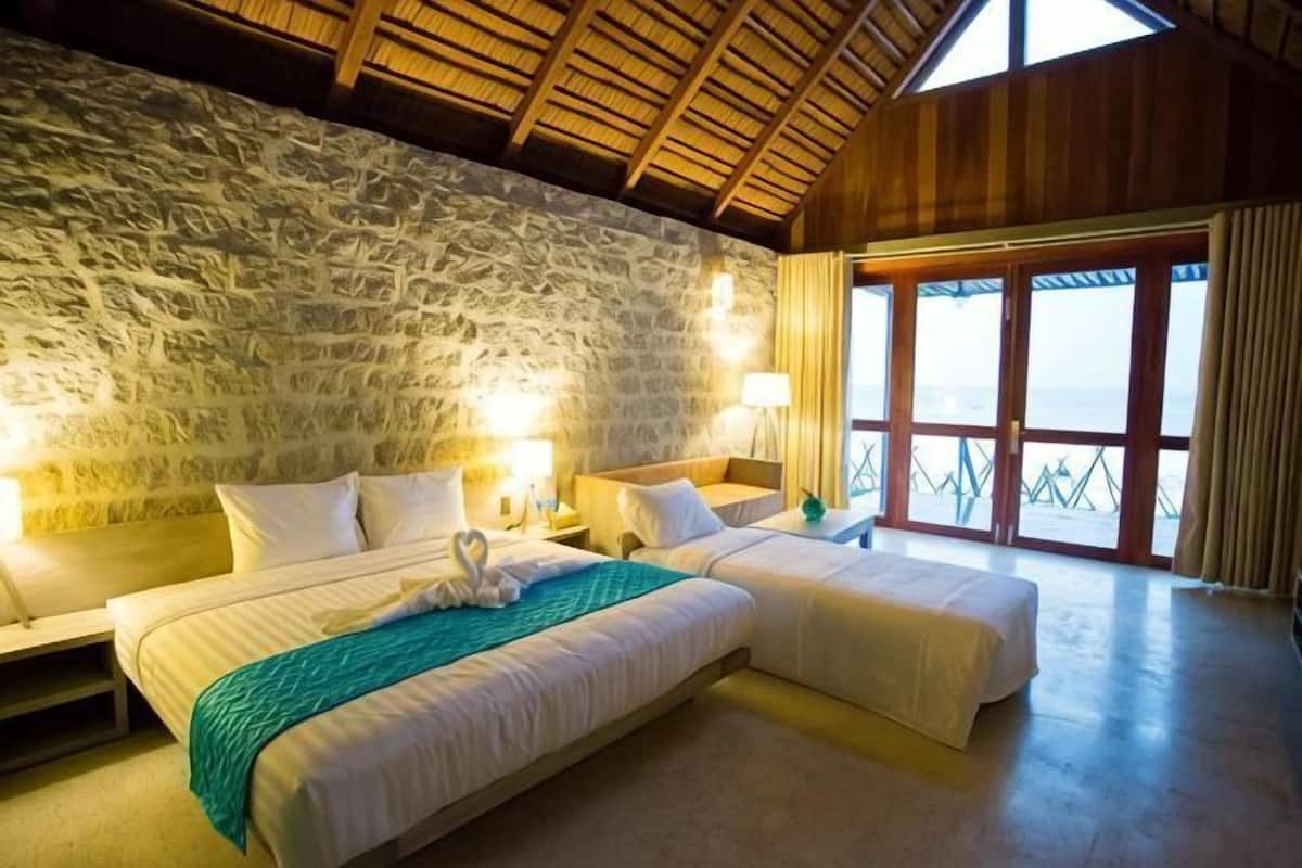 Ein Zimmer mit zwei Betten, Steinwänden, Holzboden und einem großen Fenster mit Blick.
