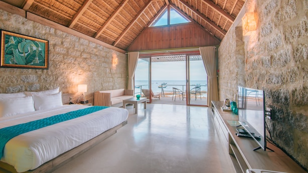 A bedroom with a large bed, a TV, and a view of the beach. - Casa Marina Resort (Quy Nhon Nam)