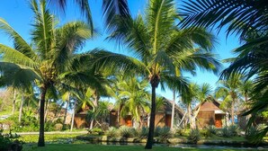A tropical resort with palm trees, a well-maintained lawn, and a clear sky. - Casa Marina Resort (Quy Nhon Nam)