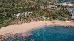 An aerial view of a beach resort with multiple bungalow-style accommodations, a sandy beach, and a clear blue sea. - Casa Marina Resort (Quy Nhon Nam)