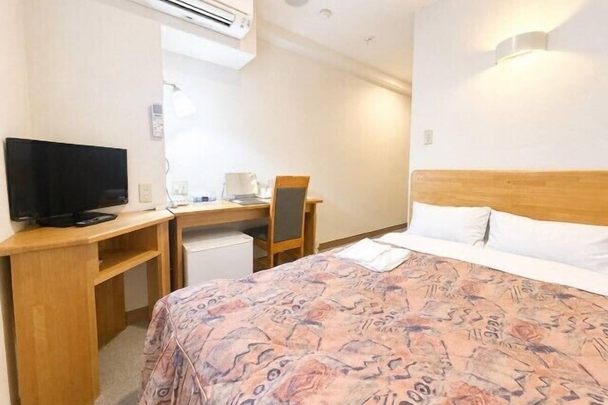 Une chambre d’hôtel équipée d’un lit, d’un bureau avec un ordinateur, d’une télévision et d’un appareil de climatisation.
