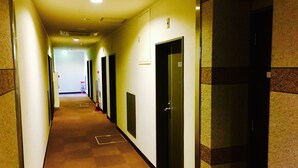 A hotel corridor with doors numbered 103, 104, and 105, carpeted floors, and a fire hydrant at the end.