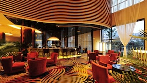 A lobby with red chairs, a patterned carpet, and large windows. - Longting New Century Hotel Qiandao Lake (Hangzhou)