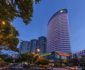 Un hotel moderno con fachada curva, señalización iluminada y una entrada destacada.