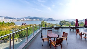 A terrace with outdoor seating, overlooking a body of water and distant mountains. - Longting New Century Hotel Qiandao Lake (Hangzhou)