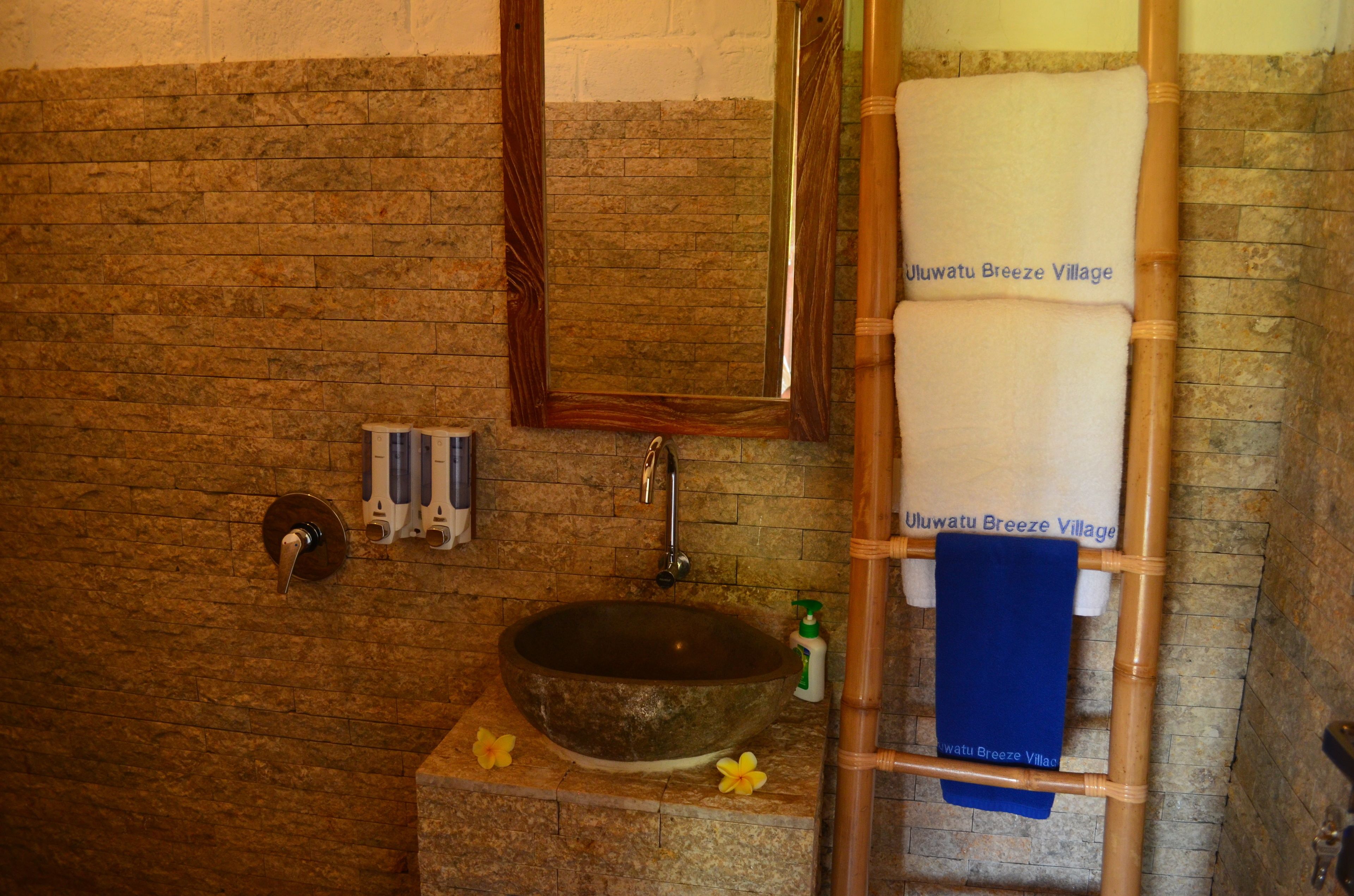 A bathroom with a stone sink, a mirror, and a towel rack with towels.