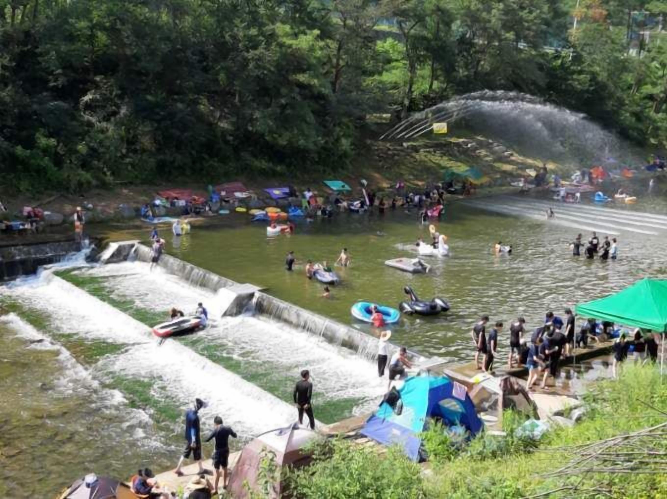 A water park with multiple water slides and a crowd of people enjoying the facilities.