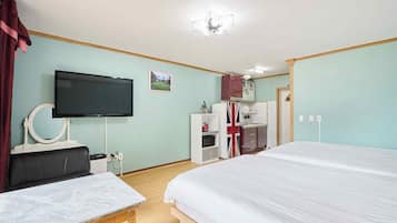 A hotel room with a bed, a TV, a desk, a mirror, a wardrobe, and a kitchenette.