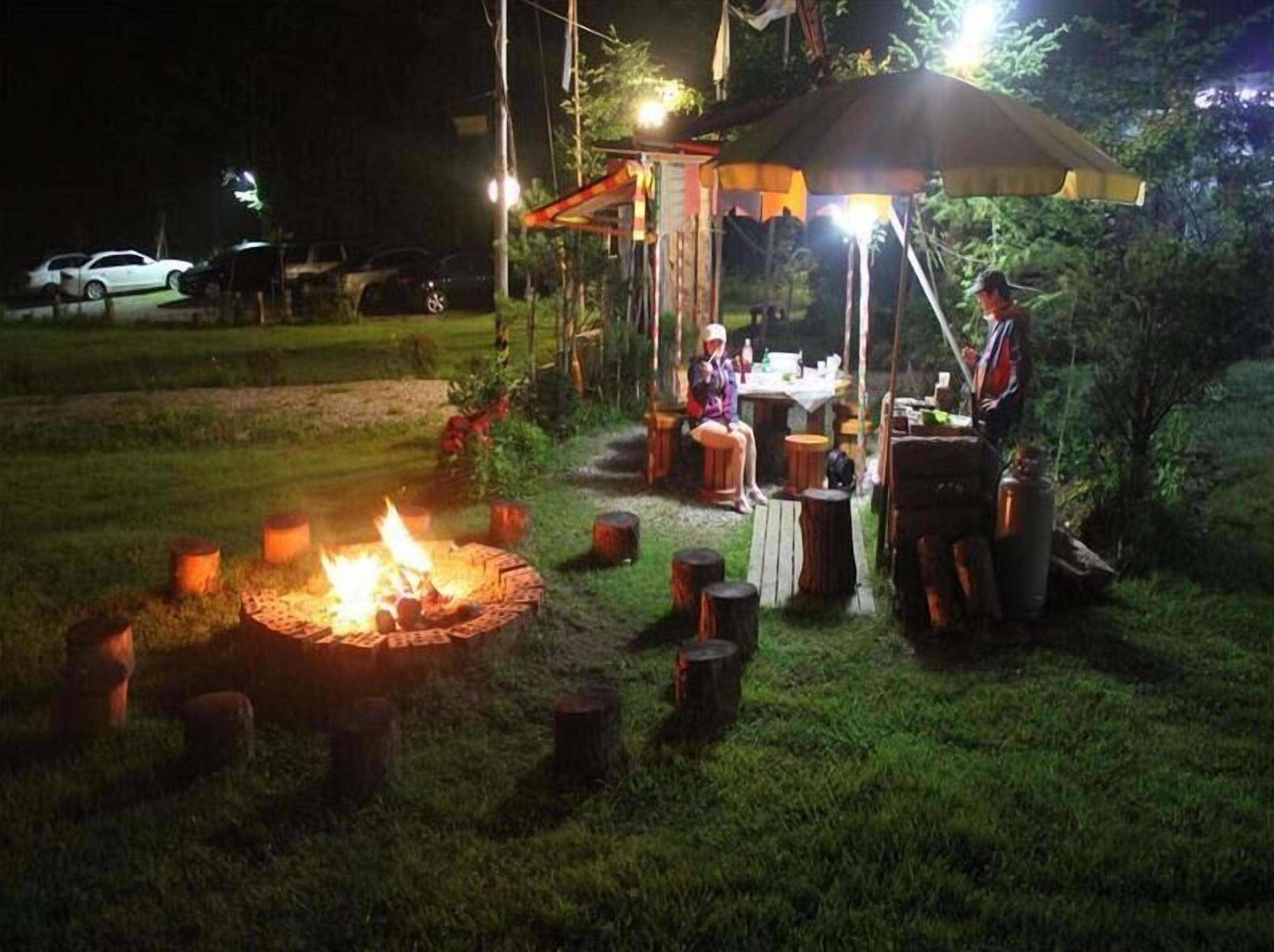 An outdoor dining area with a fire pit, tables, and a canopy.