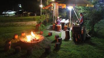 An outdoor dining area with a fire pit, tables, and a canopy.