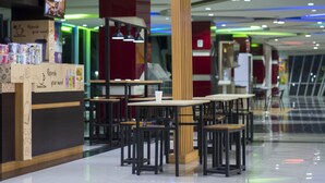 Un moderno comedor interior con mesas y sillas, una barra con un menú, y una pantalla de televisión.